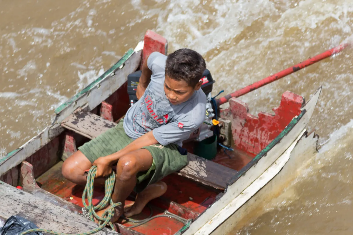 Boy in a canoe hooking onto the riverboat, Lower Amazon, Brazil — Nicolas Marincic