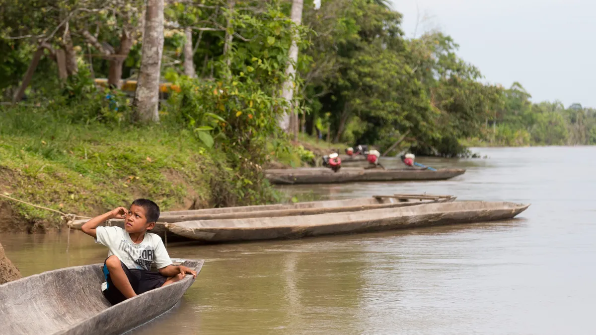 Enfant dans une pirogue au bord du fleuve, Pérou — Nicolas Marincic