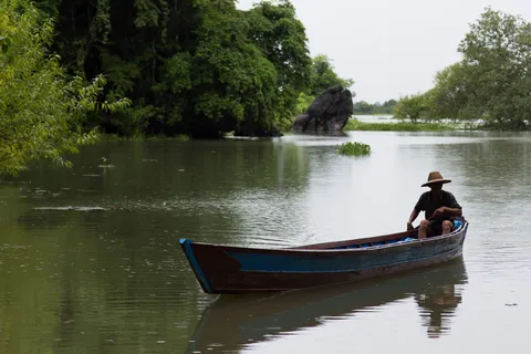 Boatman on a river below limestone outcrops, Burma — Nicolas Marincic