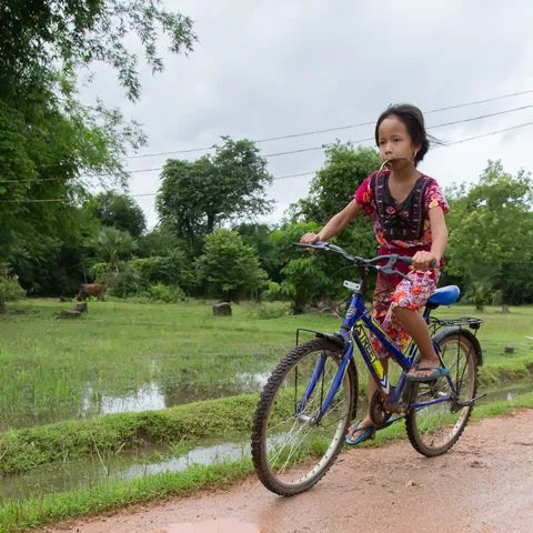 Girl cycling between the paddies, Burma — Nicolas Marincic