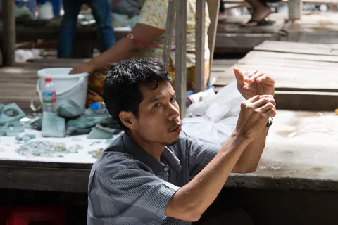 Trader examining a stone at the jade market, Burma — Nicolas Marincic