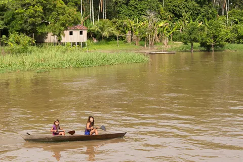Children paddling a canoe on the river, Brazil — Nicolas Marincic