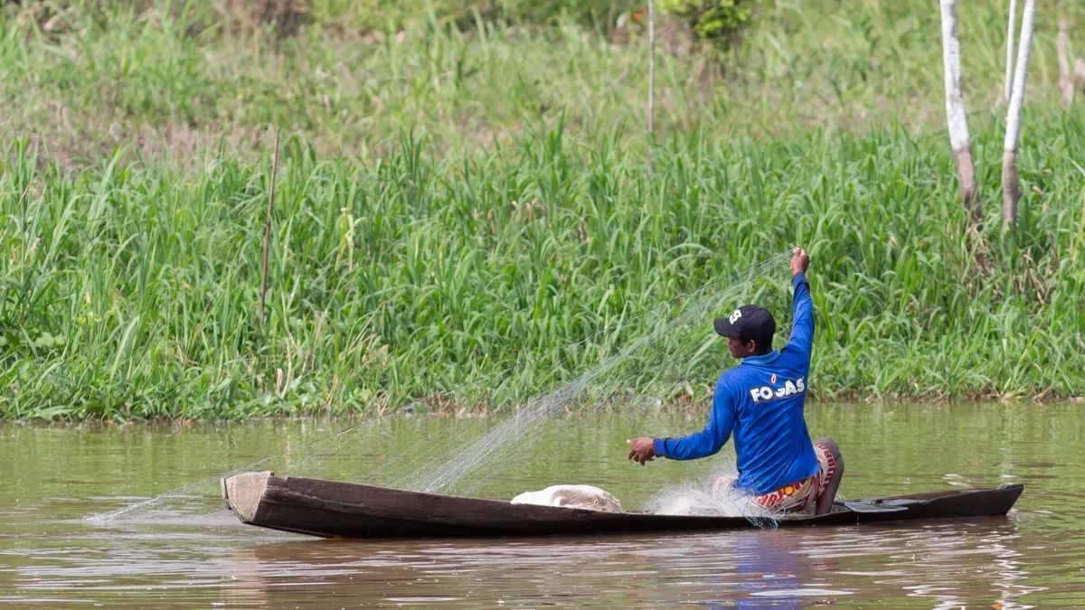 Fisherman casting his net from a canoe, Brazil — Nicolas Marincic