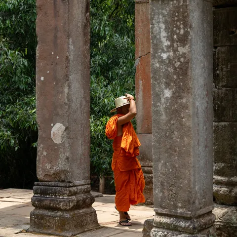Monk in saffron robe between the columns of Ta Prohm, Cambodia — Nicolas Marincic