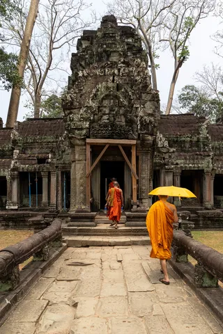 Monks with a yellow umbrella at the gate of Ta Prohm, Cambodia — Nicolas Marincic