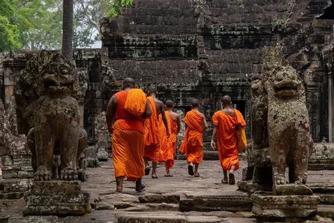 Monks between a temple’s stone lions, Cambodia — Nicolas Marincic
