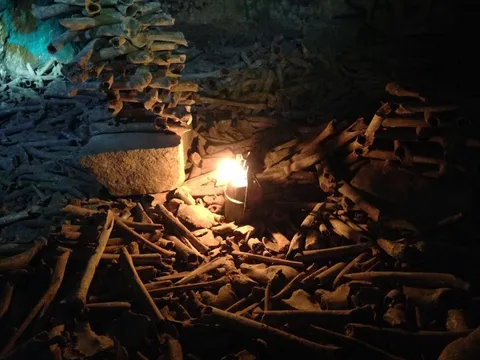 Heaps of bones by candlelight in the ossuary, France — Nicolas Marincic