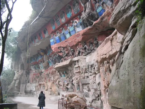 Carved cliff at Dazu with a visitor for scale, China — Nicolas Marincic
