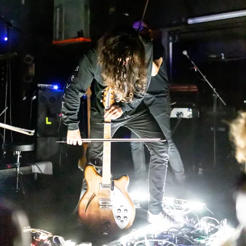 Bruit ≤ guitarist bent over a glowing pedalboard, France — Nicolas Marincic