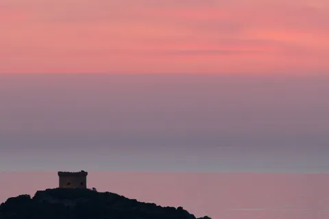 Genoese tower silhouetted at pink dusk, Corsica, France — Nicolas Marincic