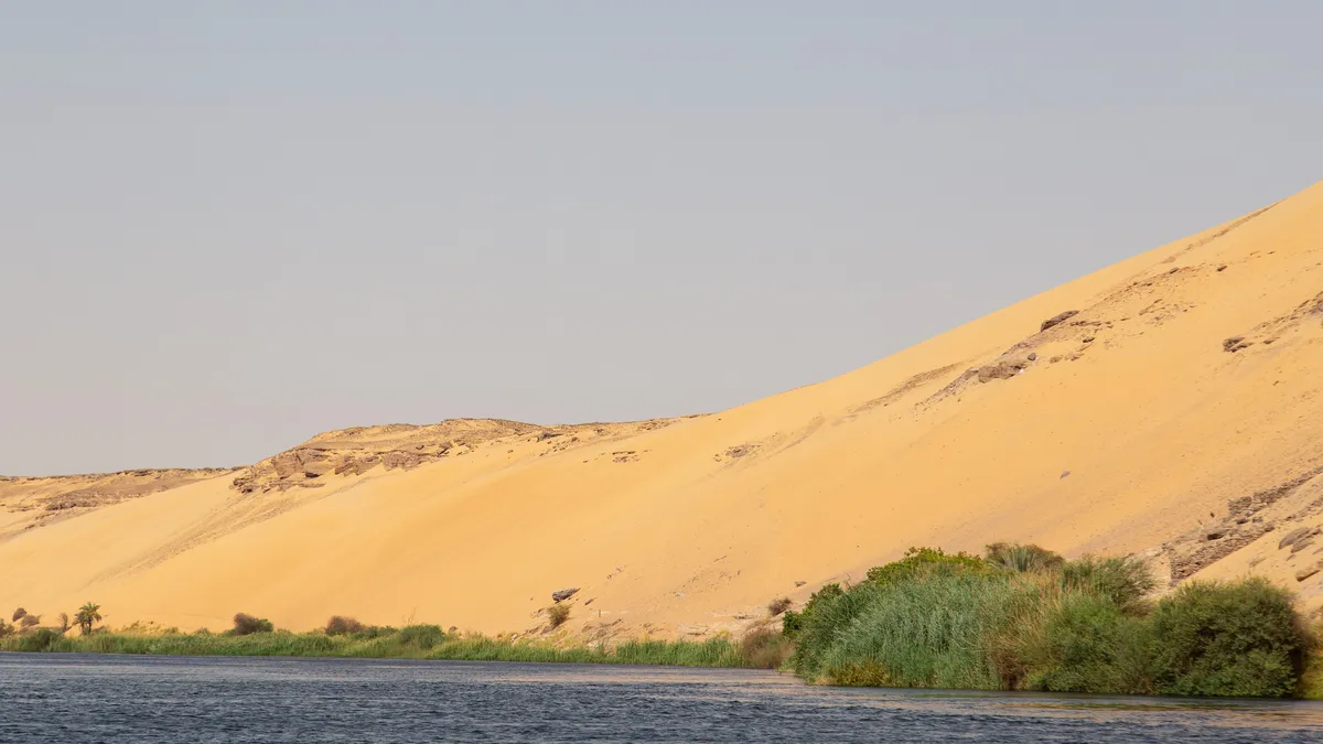 Golden dune sloping into the Nile, Aswan, Egypt — Nicolas Marincic
