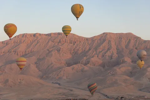 Balloons drifting over the pink Theban hills, Egypt — Nicolas Marincic