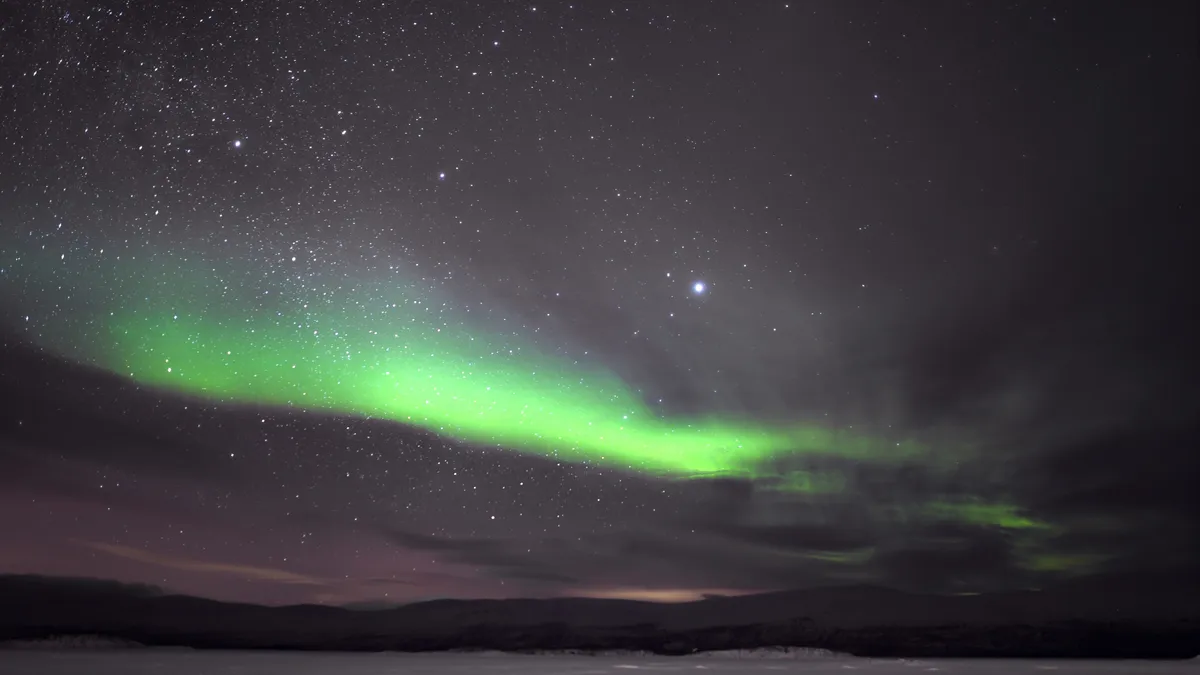 Green auroral arc over snowy land, Sweden — Nicolas Marincic