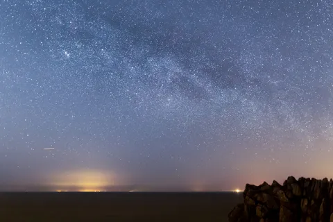 Milky Way rising over the sea from a rocky coast, France — Nicolas Marincic
