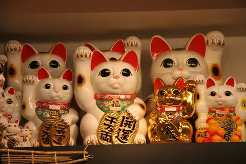 Maneki-neko lined up on a shelf, Japan — Nicolas Marincic