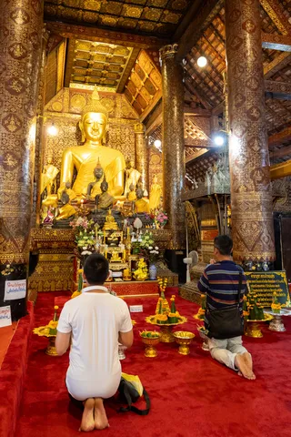 Worshippers praying before a golden Buddha, Laos — Nicolas Marincic