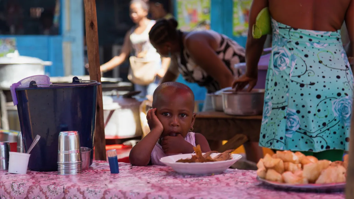 Child at a fritter stall, Madagascar — Nicolas Marincic