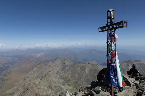 Summit cross with prayer flags, Italy — Nicolas Marincic