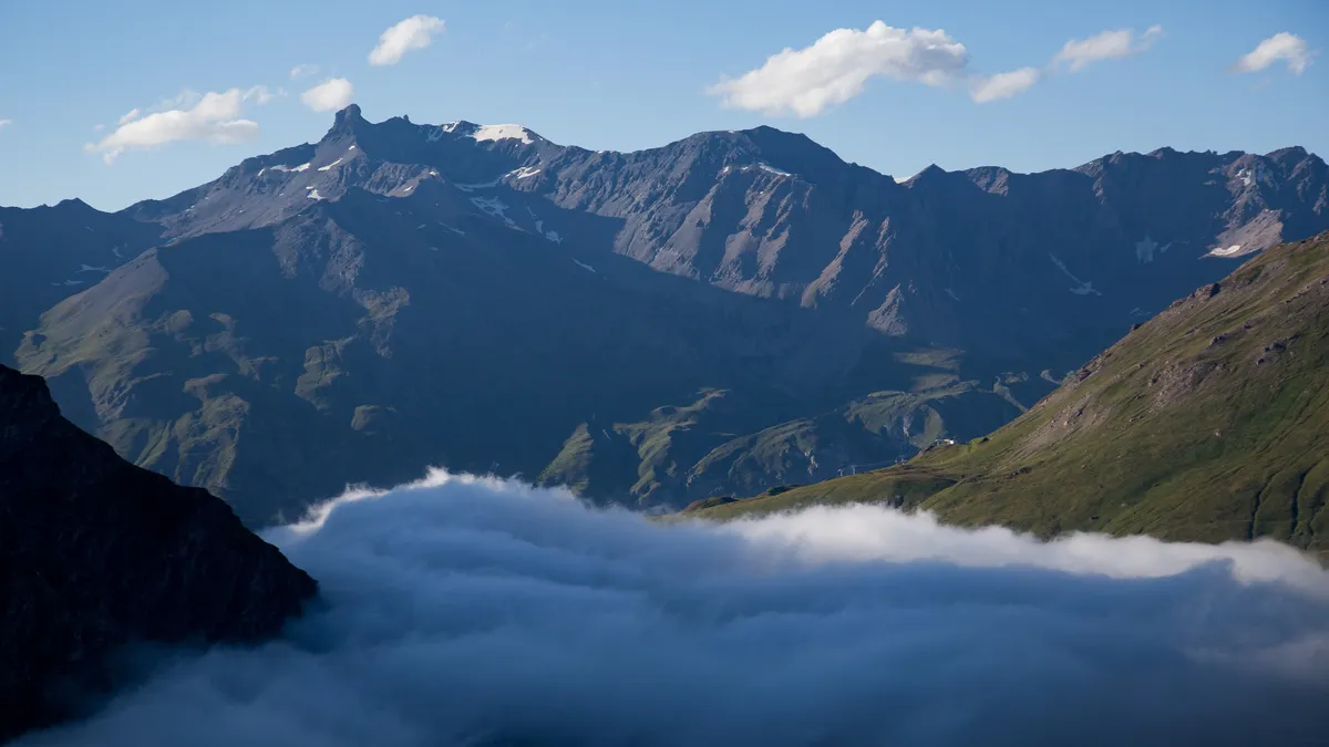 River of cloud beneath jagged ridges, Mont-Cenis, France — Nicolas Marincic