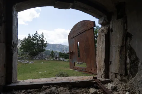 Rusted door of a derelict fort opening onto the mountains — Nicolas Marincic