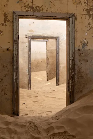 Nested doorways and drifting sand, Kolmanskop, Namibia — Nicolas Marincic