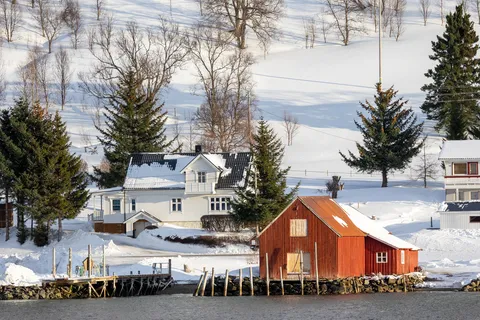Hangar à bateaux rouge et ferme blanche sous la neige, Norvège — Nicolas Marincic