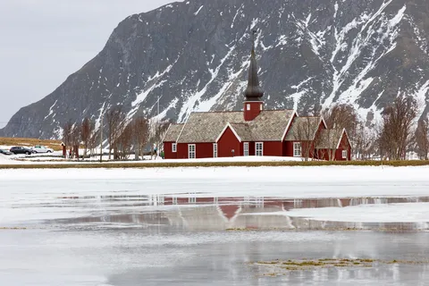 Église rouge de Flakstad et son reflet sous un sommet enneigé, Norvège — Nicolas Marincic