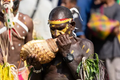 Man blowing a conch shell, Papua — Nicolas Marincic