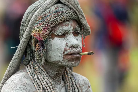 Man covered in white clay, cigarette in mouth, Papua — Nicolas Marincic