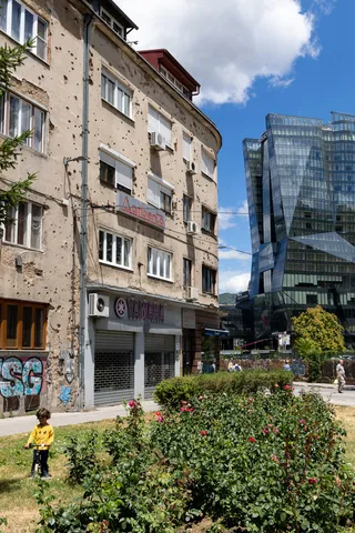 Shell-scarred building facing glass towers, Sarajevo, Bosnia and Herzegovina — Nicolas Marincic