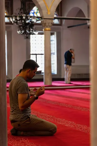Man praying on a red carpet, Yeni Cami, Istanbul, Turkey — Nicolas Marincic