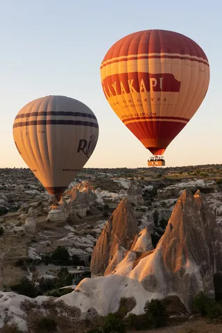 Two balloons above sunlit fairy chimneys at sunrise, Turkey — Nicolas Marincic