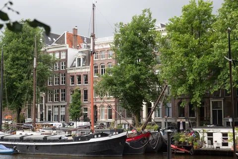 Traditional sailing barges moored before canal houses, Amsterdam, Netherlands — Nicolas Marincic