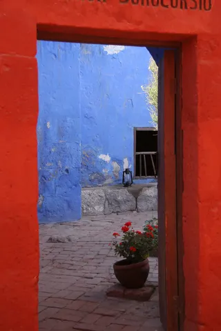 Red doorway opening onto a blue courtyard, Santa Catalina, Arequipa, Peru — Nicolas Marincic