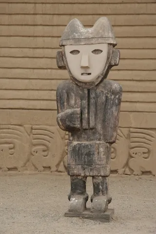 Wooden Chimú statue before adobe friezes, Chan Chan, Peru — Nicolas Marincic