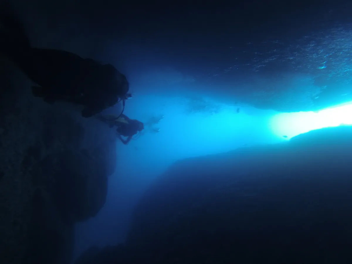 Diver silhouetted at a tunnel exit, Medes Islands, Spain — Nicolas Marincic