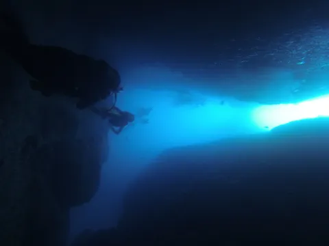 Diver silhouetted at a tunnel exit, Medes Islands, Spain — Nicolas Marincic