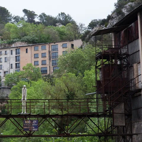 Abandoned factory and rusted walkways in a wooded gorge, France — Nicolas Marincic