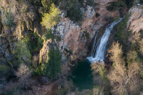 Cascade dans un bassin vert au fond d’une gorge boisée, France — Nicolas Marincic