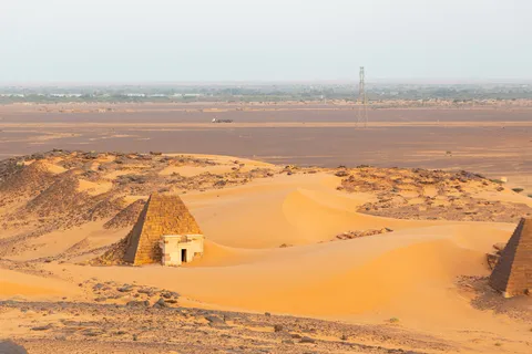 Meroë pyramid half-buried in orange dunes, Sudan — Nicolas Marincic