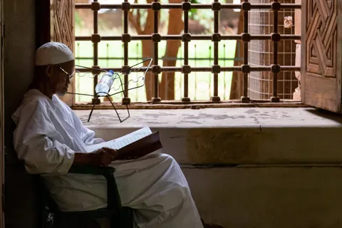Man reading the Quran by a carved window, Omdurman, Sudan — Nicolas Marincic