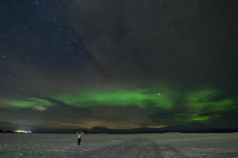 Silhouette sous l’aurore boréale sur un lac gelé, Suède — Nicolas Marincic
