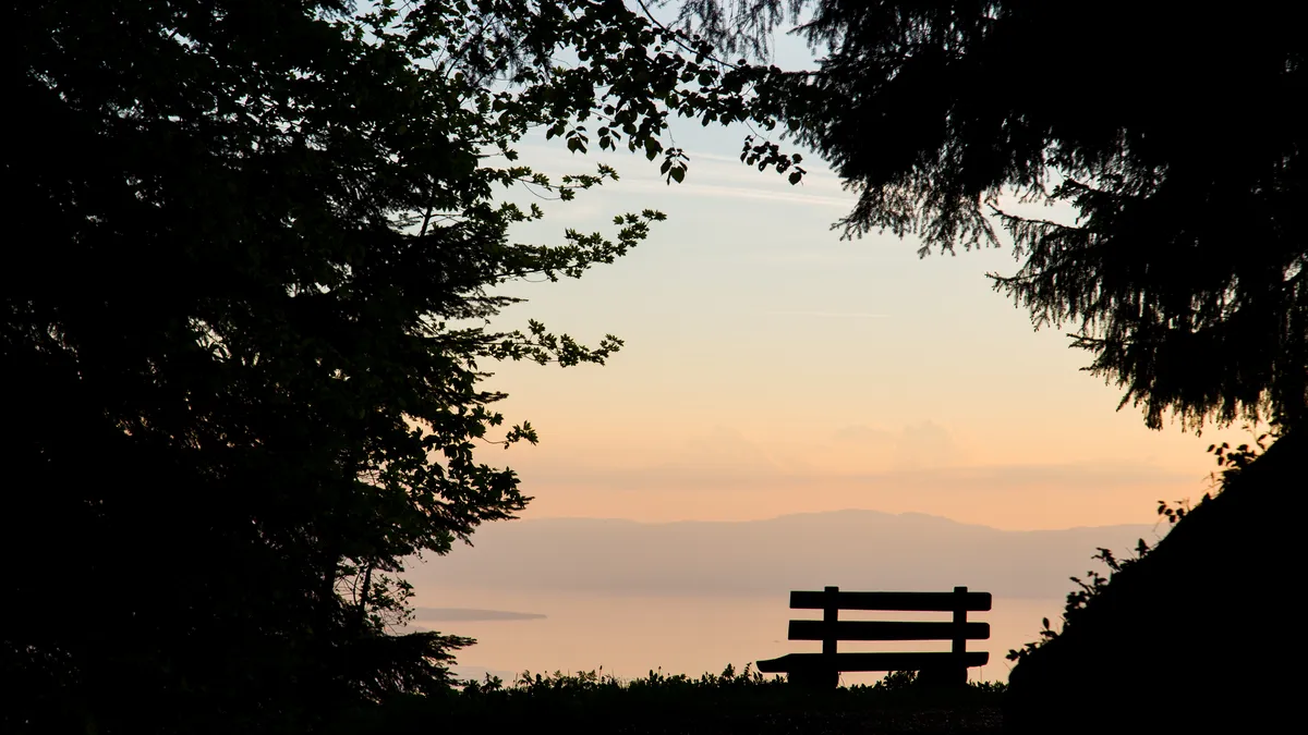 Empty bench silhouetted at sunset, Lake Geneva, Switzerland — Nicolas Marincic