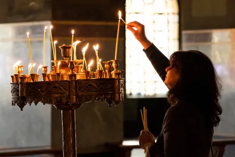 Woman lighting a candle in a church, Czechia — Nicolas Marincic