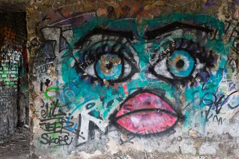 Graffiti face with blue eyes and pink lips in a ruin, France — Nicolas Marincic