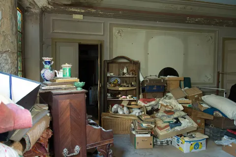 Salon frozen in time, piled with abandoned belongings, France — Nicolas Marincic